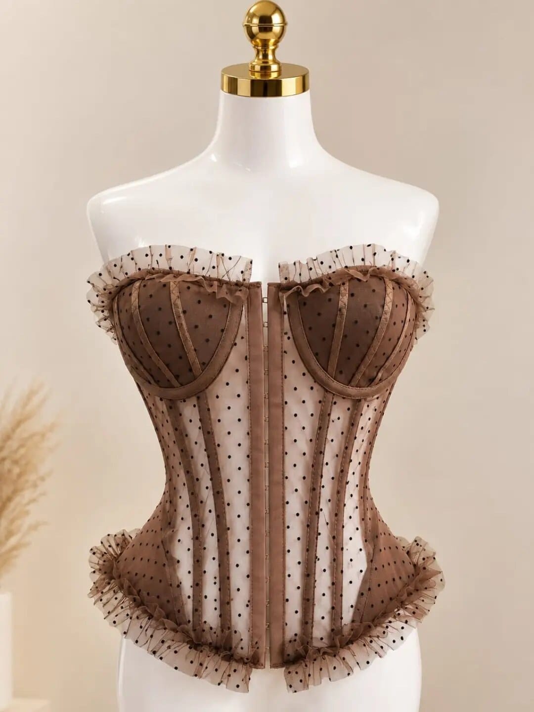 Corsé café de tul con lunares sobre maniquí, fondo beige